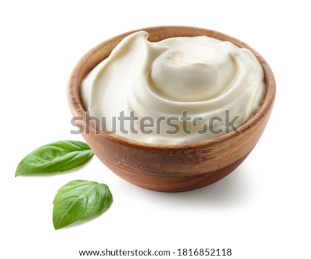 sour cream yogurt in wooden bowl and basil leaves isolated on white background