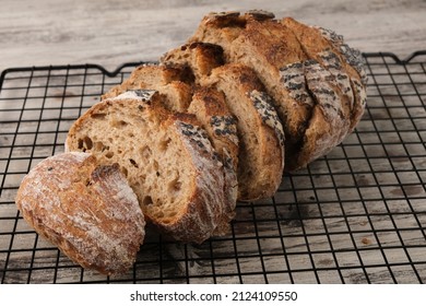 Sourdough bread in the cooling rack on the rustic table. Sourdough is a bread made by fermenting dough using wild lactobacillaceae and yeast. Lactic acid from fermentation gives sour taste and improve - Powered by Shutterstock