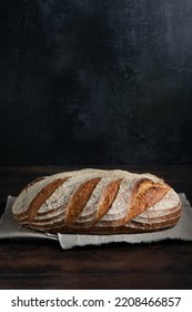 Sourdough bread. Freshly baked organic wheat bread on dark background,  with linen tablecloth. Side view. - Shutterstock ID 2208466857