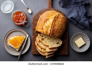 Sourdough bread on wooden cutting board with butter and orange jam. Grey background. Top view. Close up. - Shutterstock ID 2193008601