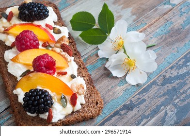 Sourdough rye bread open sandwich with ricotta,nectarine,berries,nuts and seeds with honey drizzle.