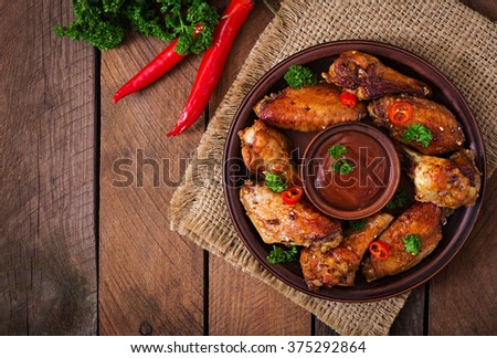 Sour-sweet baked chicken wings and sauce. Top view