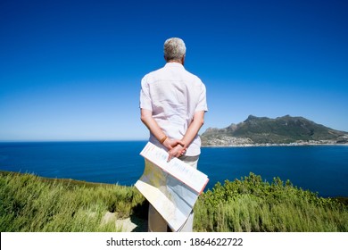 South Africa, Cape Town, senior man holding map, looking out to sea, rear view - Powered by Shutterstock