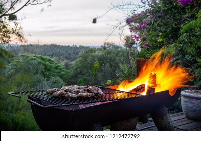A South African barbecue braai with meat on the fire in front of a lush valley landscape and a beautiful orange sunset. - Shutterstock ID 1212472792