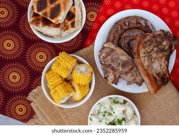 South African Braai Day or Heritage Day. Celebrating traditional braai food.
Meat and sides with traditional Shwe - Shwe cloth.
 - Shutterstock ID 2352285959