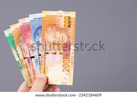 South African money - rand in the hand on a gray background