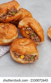 South African vetkoek, deep fried savory dough filled with saucy savory mince on mottled grey background with copy space

