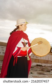 South American Native Woman With Typical Costume Playing A Small Drum In A Colonial Construction