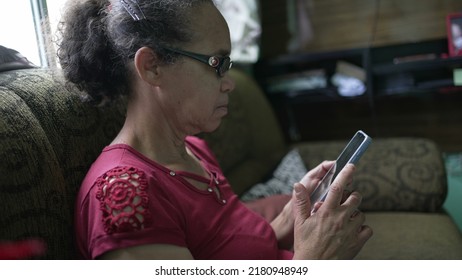 A South American Older Lady Sitting At Home Using Technology Cellphone Device