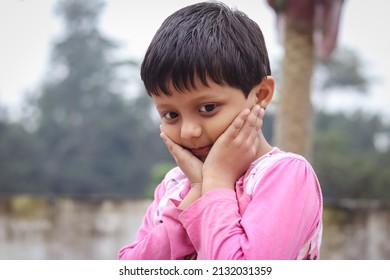 A South Asian Child In A Pink Coat Posing For A Photo Outdoors