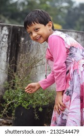 A South Asian Child In A Pink Coat Posing For A Photo Outdoors