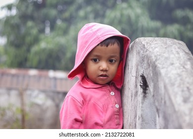 A South Asian Child In A Pink Coat Posing For A Photo Outdoors