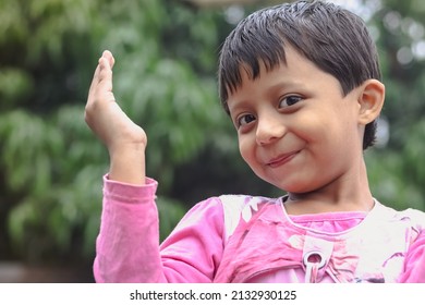 A South Asian Child In A Pink Coat Posing For A Photo Outdoors