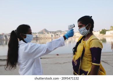 A South Asian Doctor In A Mask Checking The Temperature Of A Person With An Infrared Thermometer