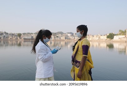 A South Asian Doctor In A Mask With An Infrared Thermometer And A Patient During The Covid-19 Pandemic