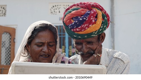 A South Asian Elder Couple In Traditional Rajasthan Indian Clothing Watching A Video On A Laptop