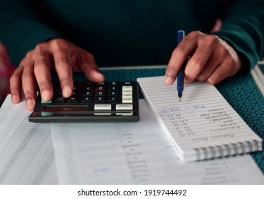 A South Asian man calculating monthly household expenses. Cost reduction, budget and financial planning concept, selective focus on the hand.