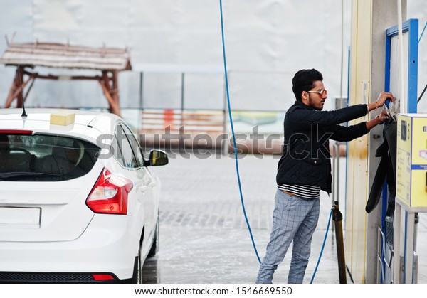 South asian man or indian male washing his white\
transportation on car\
wash.