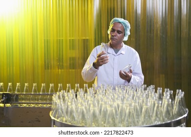 South Asian Senior Male Factory Worker Or Expert Quality Staff Is Checking Bottles Line For Beverage