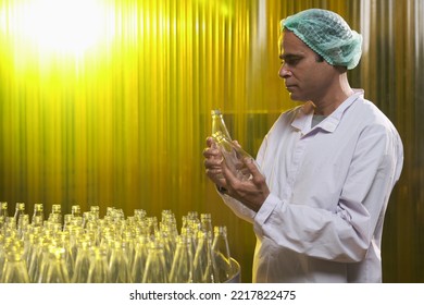 South Asian Senior Male Factory Worker Or Expert Quality Staff Is Checking Bottles Line For Beverage