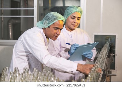 South Asian Senior Woman Factory Worker Or Expert Quality Staff Is Checking Bottles Line For Beverage