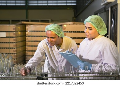 South Asian Senior Woman Factory Worker Or Expert Quality Staff Is Checking Bottles Line For Beverage