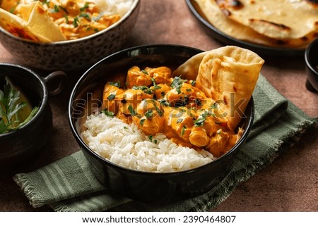 South Asian style, Indian dinner. Chicken curry with long rice and naan bread. Brown table background.