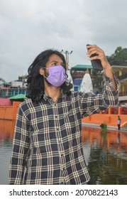 A South Asian Young Man With Long Hair Taking Selfie Or Having Video Call With His Smartphone With Wearing Face Mask While Standing Outside 