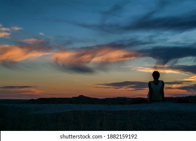 South Dakota Badlands. Woman silhouetted against a beautiful sunset on mountain top.   