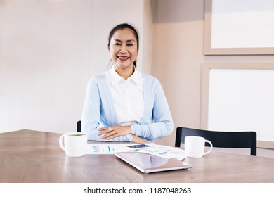 South East Asian Beautiful Middle Aged Business Woman Sitting In Cafe With Coffee Cups And Phone And Laptop