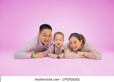 South East Asian Family Lie Down With Smile In Lovely Pink Background