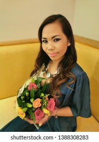 South East Asian Woman Out And About On Her Birthday Holding Flowers