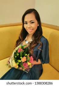 South East Asian Woman Out And About On Her Birthday Holding Flowers