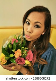 South East Asian Woman Out And About On Her Birthday Holding Flowers