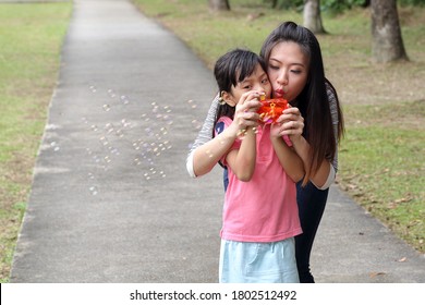 South East Asian Young Chinese Mother Daughter Parent Child Playing With Soap Bubbles Relax Activity Outdoor Park