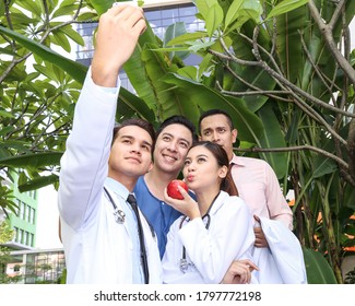 South East Asian Young Malay Chinese Man Woman Medical Doctor Stethoscope Group Holding Smart Phone Taking Selfie Self Portrait