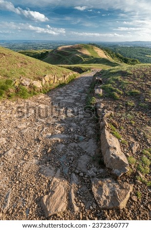 The south end of Malvern Hills,stone steps run down Hereford Beacon summit,with beautiful views across the ancient hillfort,towards Gloucestershire,on a sunny,late afternoon in British summertime.