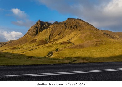 South Iceland mountain landscape along Ring Road in Vik i Myrdal villages area with volcanic mountain ridge covered with moss, sunset view, Route 1 in the foreground. - Powered by Shutterstock