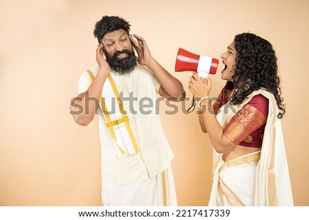 South indian wife scream or shouting at husband in megaphone isolated on beige background. announce discounts sale. Mental health. Relationship difficulty, Couple fighting. Hurry up. Marriage problems