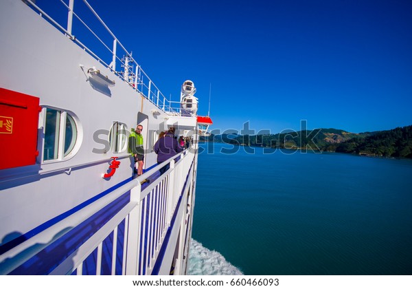SOUTH ISLAND, NEW ZEALAND- MAY 25, 2017:\
Unidentified people enjoying the beautiful view from South island\
to North island at ferry, some orange boats on one side of the\
ferry, in New Zealand