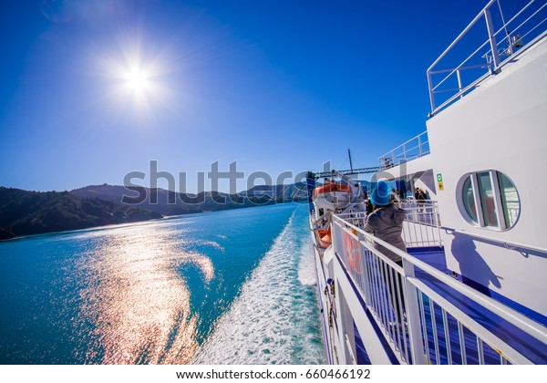 SOUTH ISLAND, NEW ZEALAND- MAY 25, 2017:\
Unidentified people enjoying the beautiful view from South island\
to North island at ferry, some orange boats on one side of the\
ferry, in New Zealand