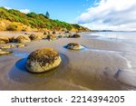 The South Island of New Zealand. Sandy beach on the Pacific Ocean. Moeraki boulders is a group of huge stones and their remains. The concept of exotic and ecological tourism