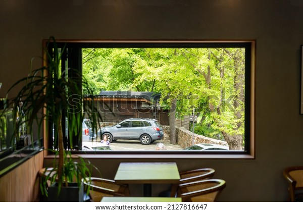 South Korea,May 2021: View\
of a korean car parking at the outside garden from a cafeteria\
window frame.