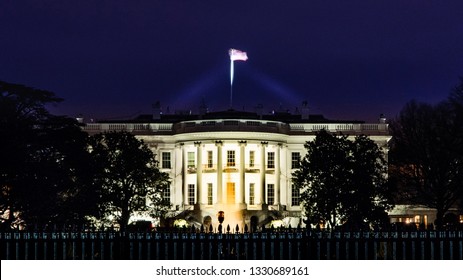 South Lawn View Of The White House, Presidential Residence At Night In Winter With The Structure Illuminated And Steel Fence In The Foreground.