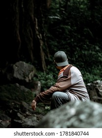 South Pesisir, Indonesia - 7/19/2020 : Man Squat Down Next To The Woods Near Ambun Sarasah Waterfall