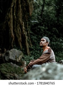 South Pesisir, Indonesia - 7/19/2020 : Man Squat Down Next To The Woods Near Ambun Sarasah Waterfall