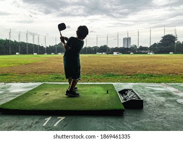 South Tangerang, Indonesia - November 16, 2020: Young Kid Golf Downswing Follow Thru At Driving Range From Back Side View. Backlighting Photo