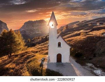 South Tyrol, Italy - The setting sun is shinning through the Chapel of San Maurizio (Cappella Di San Maurizio) at the Passo Gardena Pass in the Italian Dolomites at autumn with warm sunlight