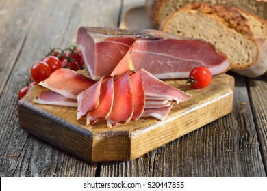 South Tyrolean bacon with fresh stone oven baked bread on a wooden table