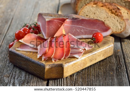 South Tyrolean bacon with fresh stone oven baked bread on a wooden table